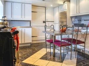 a kitchen with white cabinets and a table and chairs at Foxstones Farm House in Worsthorne