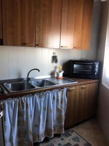 eine Küche mit einer Spüle und einer Mikrowelle in der Unterkunft Appartamento luminoso e spazioso al primo piano in Capoterra