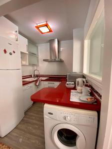 kuchnia z pralką i czerwonym blatem w obiekcie Magic Point Sevilla w Sewilli