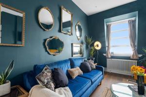 a blue living room with a blue couch and mirrors at Modern 1 Bed Apartment, Sea Views, free parking, wifi, netflix in Teignmouth