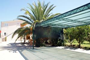 a metal pavilion with a palm tree behind it at Apartments Kairos - Bili 9 in Kaštela