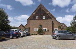 een groot bakstenen gebouw met auto's geparkeerd op een parkeerplaats bij Converted church in Beckenham