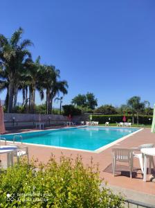 a swimming pool with tables and chairs and palm trees at Sun House Sicily in Mascali