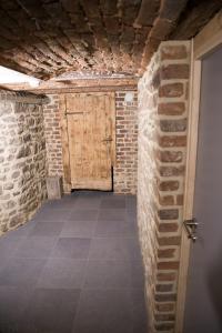 a hallway with a wooden door in a brick wall at Gite Kooa Prestige in Theux