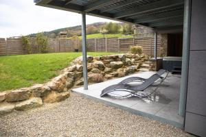 a bench sitting on a patio with a stone wall at Gite Kooa Prestige in Theux
