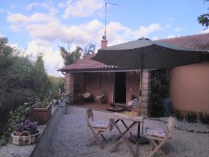 un patio con mesa, sillas y sombrilla en roncio' cottage, en Ronciglione