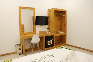 a room with a desk with a television and a mirror at Alaika Maafushi in Maafushi