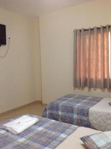 a bedroom with two beds and a window at Hotel Colonial in Pôrto Real
