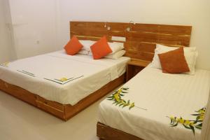 two beds sitting next to each other in a bedroom at Alaika Maafushi in Maafushi