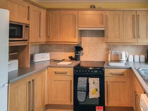 uma cozinha com armários de madeira e uma máquina de lavar louça preta em Marrion House em Middleton