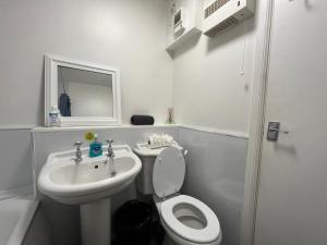 a white bathroom with a toilet and a sink at River View Apartment in Elgin