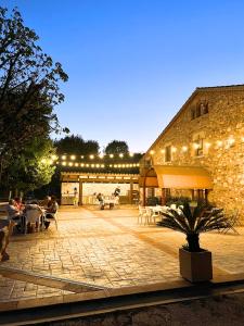 un patio con luces y mesas y un edificio en Mas Segart, en Santa María de Palautordera