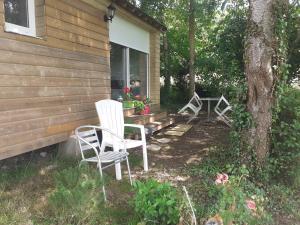 2 Stühle und ein Tisch außerhalb eines Hauses in der Unterkunft Maison d'hôtes indépendante à la campagne in Ablon