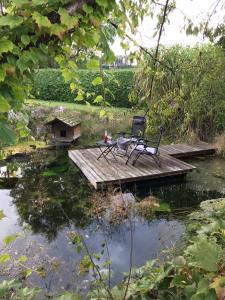 une table et des chaises assises sur un pont en bois au-dessus d'un étang dans l'établissement Klopeinerperle, à Peratschitzen