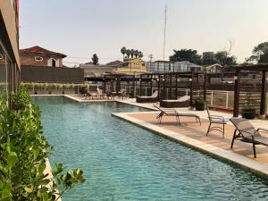 a swimming pool with chairs in a building at Apartamento Wi-fi, Split, Estacionamento e Piscina in Ribeirão Preto