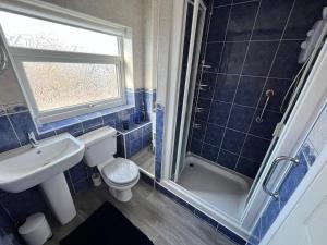uma casa de banho com um WC, um lavatório e um chuveiro em Seaside 2 bedroom house with large garden em Rhyl