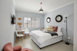 a bedroom with a bed and a table with a chair at Sea Breeze Apartments in Bloubergstrand