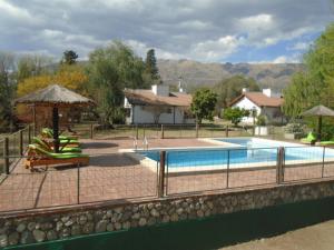 a pool with chairs and umbrellas next to a house at Aldea Blanca in Merlo