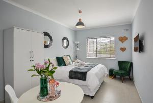 a bedroom with a bed and a table and a chair at Sea Breeze Apartments in Bloubergstrand