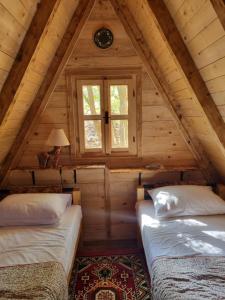 duas camas no sótão de um chalé de madeira em Wolf & Sheep Nature & Adventure em Podgorica