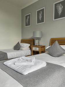 ein Zimmer mit 2 Betten und weißen Handtüchern darauf in der Unterkunft Aragon House in Peterborough