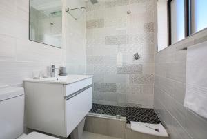 a white bathroom with a sink and a shower at Sea Breeze Apartments in Bloubergstrand