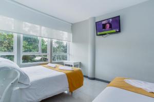 1 dormitorio con 2 camas y TV en la pared en ApartaSuites & Hotel Bogota Suamox, en Bogotá