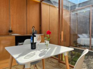 Una mesa blanca con una botella de vino y una rosa. en Deluxe volcán Primeras suites colgantes del mundo en Baños