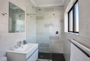 a white bathroom with a sink and a mirror at Sea Breeze Apartments in Bloubergstrand