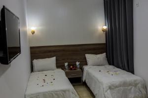 duas camas num quarto de hotel com flores em HOTEL BORJ SAFAE LAAYOUNE em Laayoune