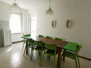 a dining room with a wooden table and green chairs at Villa Villi in Terlago