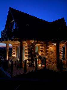 une cabane en rondins avec terrasse la nuit dans l'établissement Little House, à Ząb