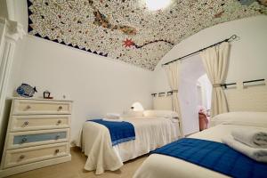 a bedroom with two beds and a ceiling with a mural at Casa Cueva Los Mosaicos in Guadix