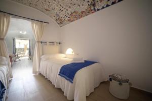 a bedroom with a white bed with a blue blanket at Casa Cueva Los Mosaicos in Guadix