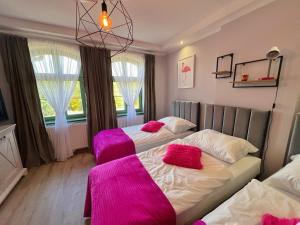 2 łóżka w pokoju z różowymi kocami w obiekcie Pokoje Pod Mniszkiem w mieście Boguszów-Gorce