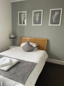 a bedroom with a large white bed with three pictures on the wall at Aragon House in Peterborough