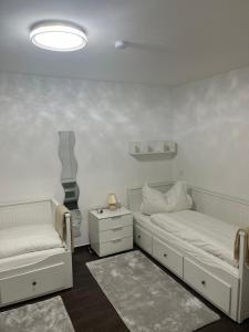 a white bedroom with two beds and a night stand at Bibis Ferienwohnung in Munich