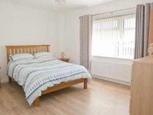 a white bedroom with a bed and a window at Maple Cottage in Drumshanbo-Glebe