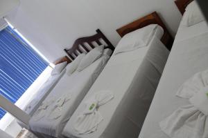 a bedroom with two beds with white sheets and a window at Pousada Oliveira in Foz do Iguaçu +7 photos