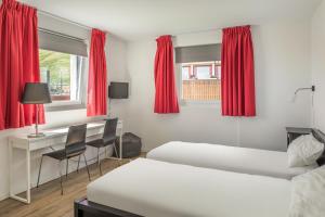 FieschertalにあるBella Vistaのベッドルーム1室(ベッド2台、デスク、赤いカーテン付)