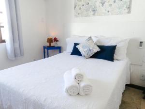Un dormitorio con una cama blanca con toallas. en Viva Búzios Flats, en Búzios