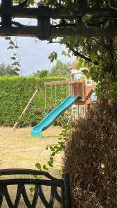 um parque infantil com um escorrega azul num quintal em The GateHouse at Stansted em Hallingbury