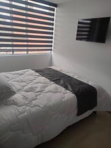 1 dormitorio con 1 cama grande y ventana en Hotel Cacique, en Duitama