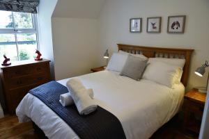 een slaapkamer met een bed met witte lakens en kussens bij The Gardeners Cottage in Pitlochry