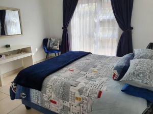 a bedroom with a bed with a comforter and a window at 29 Jeffs Place in Yzerfontein