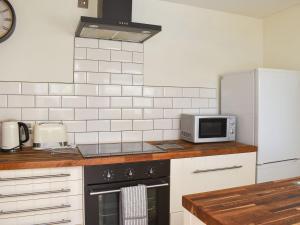 a kitchen with a stove and a microwave at Sunbury Cottage in Clanfield