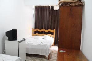 um quarto de hotel com uma cama e uma televisão e um quarto em Pousada Oliveira em Foz do Iguaçu