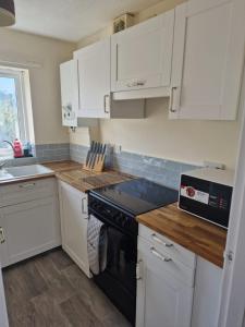 a kitchen with white cabinets and a black stove at Lovely 2 bed appt with parking only 5 mins from M6 or Carlisle in Carlisle