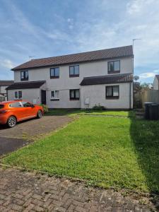 un coche naranja estacionado frente a una casa en Lovely 2 bed appt with parking only 5 mins from M6 or Carlisle en Carlisle