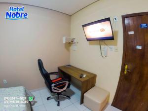 a room with a desk and a chair and a television at Hotel Nobre in Senhor do Bonfim
